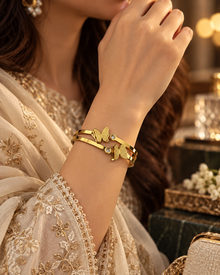 Noor gold butterfly cuff bracelet worn on wrist with cream embroidered outfit