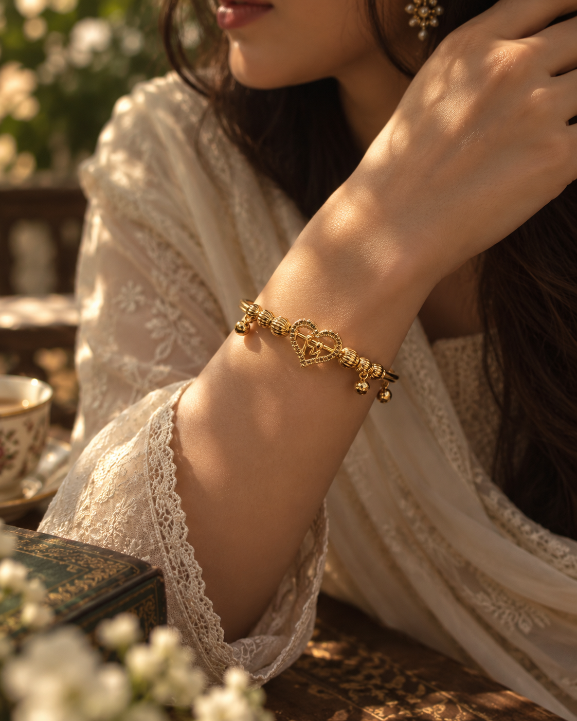 Ayla gold heart charm bracelet worn with elegant cream embroidered outfit