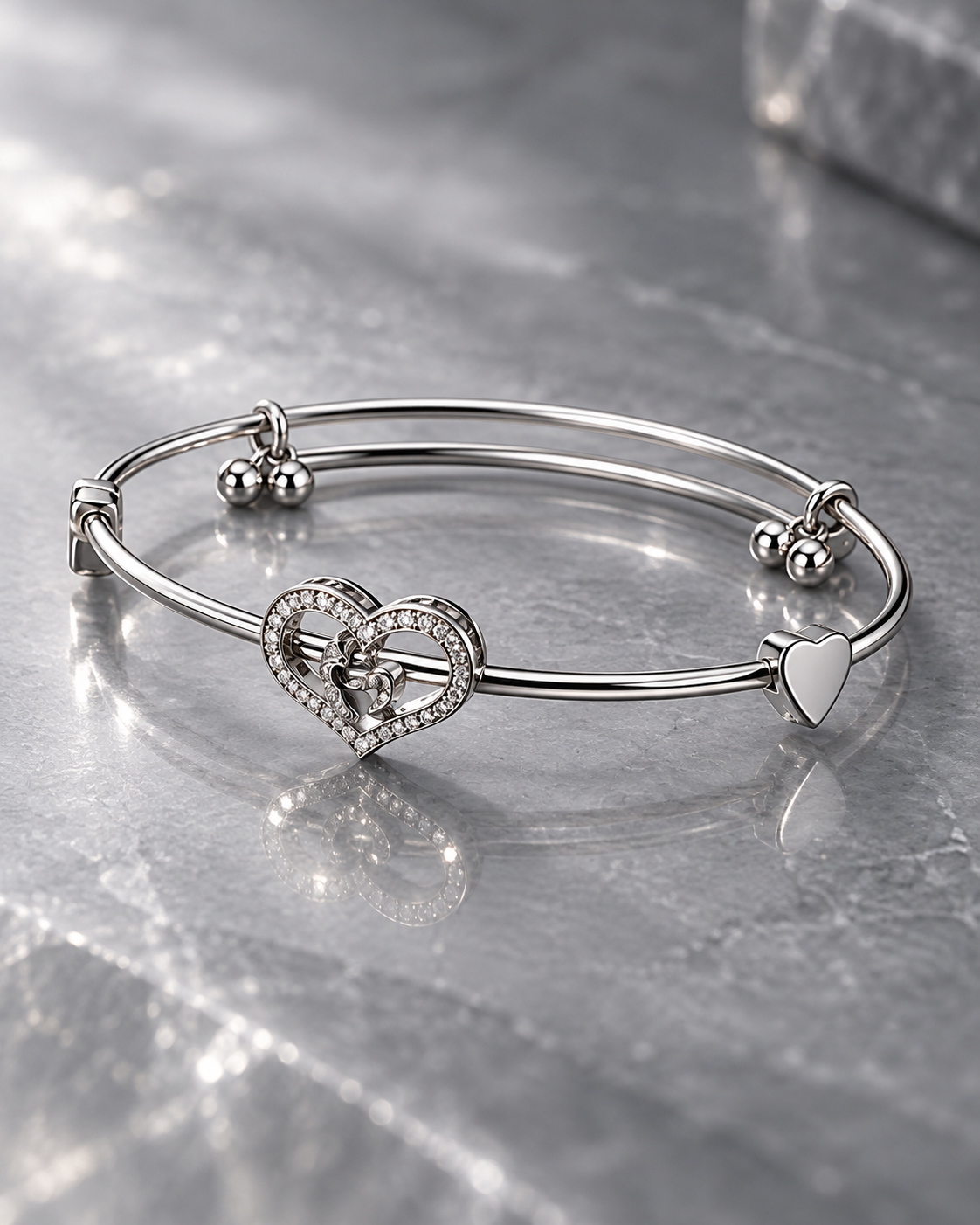 Elara silver-tone crystal heart bangle shown from the side on a polished marble surface