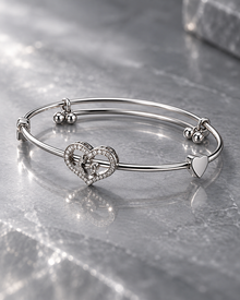 Elara silver-tone crystal heart bangle shown from the side on a polished marble surface