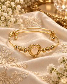 Mira Gold heart bangle worn with Mira Gold heart charm bangle with textured beads styled on ivory silk