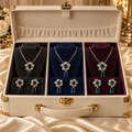 Liora floral necklace and earrings sets in Black, Sapphire Blue and Emerald Green displayed in a luxury jewellery trunk