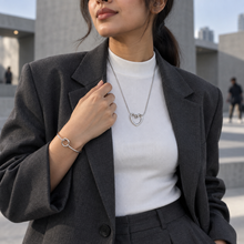 Woman styling the Silver Nova Loop Heart necklace and cuff bracelet with a charcoal blazer