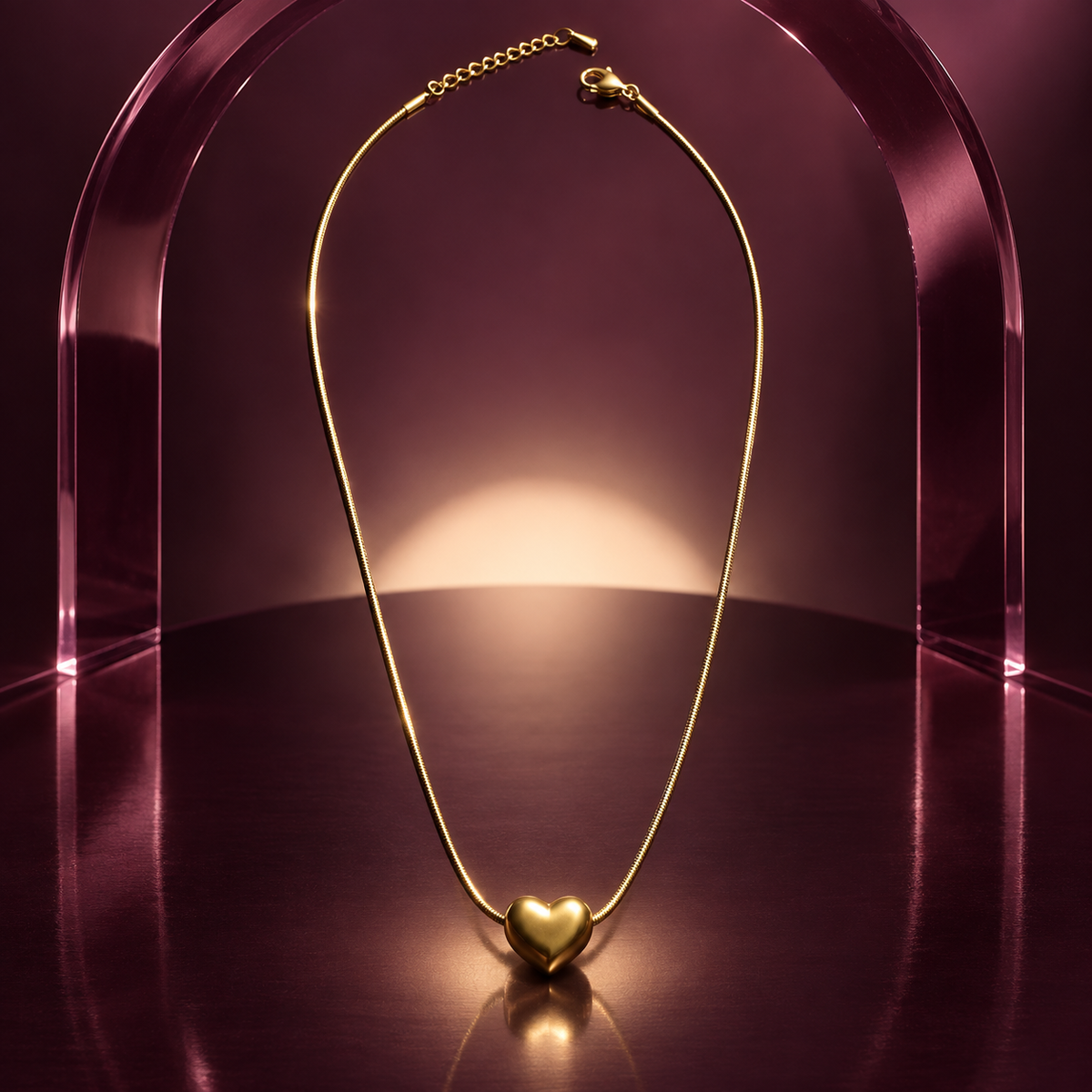 Amora gold puffed heart pendant displayed beneath a translucent plum acrylic arch