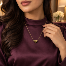 Woman in a modest plum blouse wearing the Amora gold puffed heart pendant