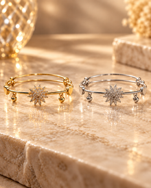 Gold and silver starburst bangle bracelet variants displayed together on a luxury marble surface