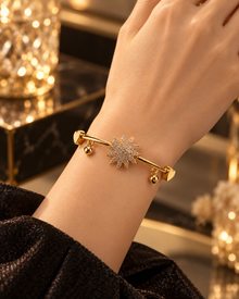 Gold starburst bangle bracelet worn on the wrist with elegant luxury styling