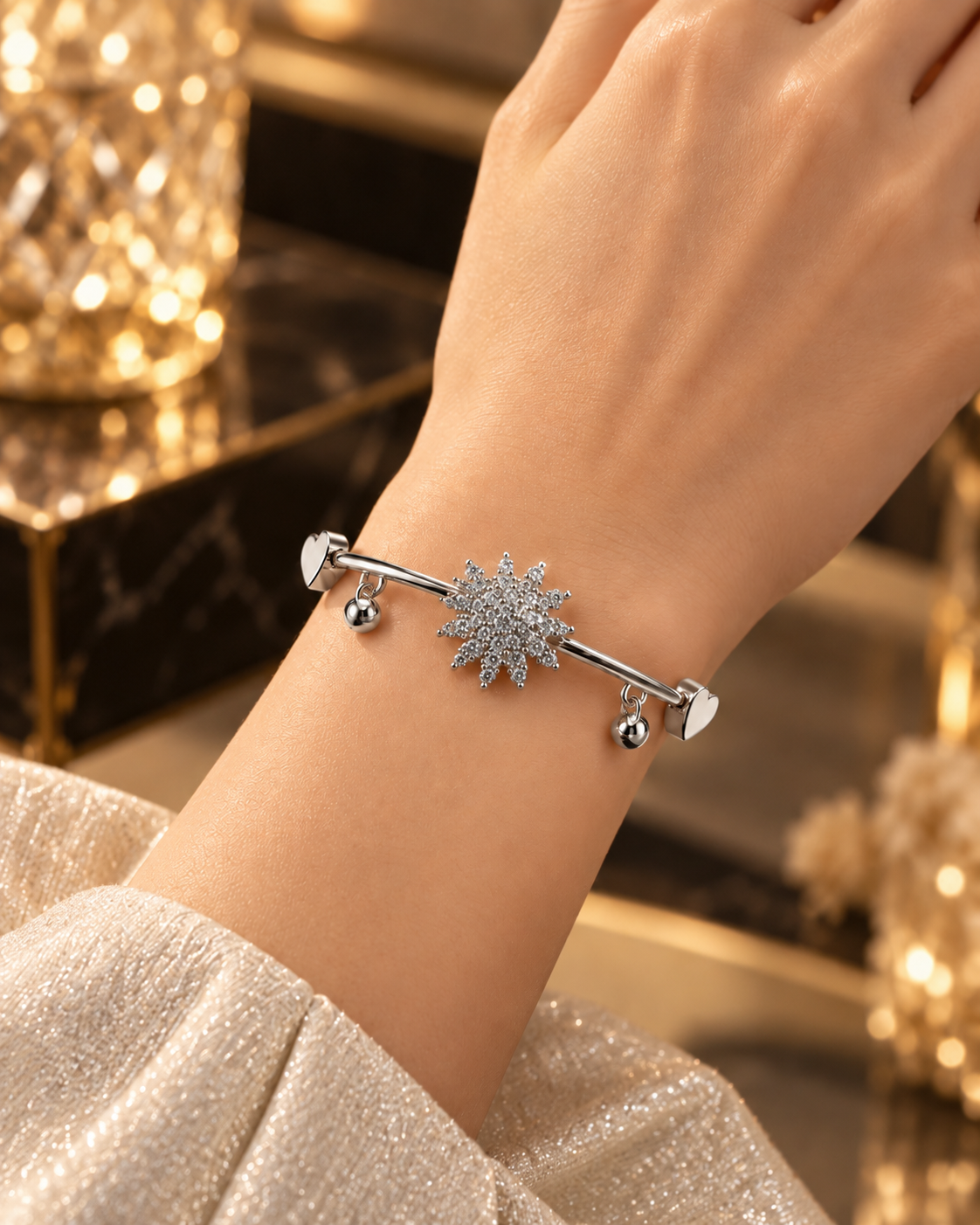 Silver starburst bangle bracelet with heart accents and dangling charms on a luxury stone surface