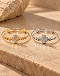 Gold and silver clover bangle bracelet variants displayed separately side by side