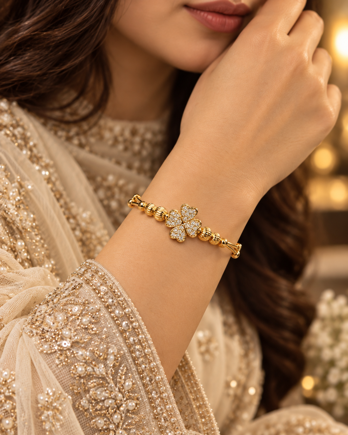 Gold clover bangle bracelet worn with elegant cream embroidered formalwear