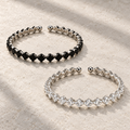 Elara Prism Bangle in Black and Clear, displayed separately on ivory stone.
