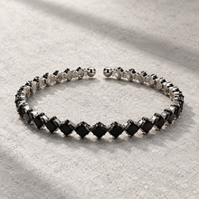 Black Elara Prism Bangle with diagonal square stones, silver-tone settings and rounded open-cuff ends.